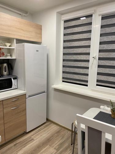 a kitchen with a white refrigerator and a table at Apartments Victoria in Panevėžys