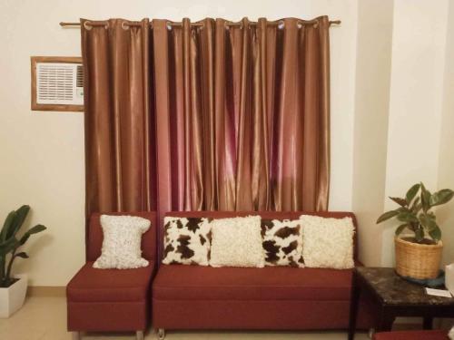 a red couch sitting in front of a curtain at Unit 3J Signature Suites, Lafayette Megaworld in Iloilo City