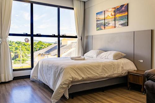 een slaapkamer met een groot bed en een groot raam bij Studio em condomínio c/ piscina 700m praia STI210 in Florianópolis