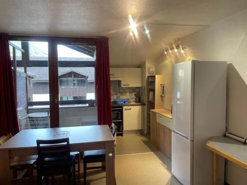 une cuisine avec une table et un réfrigérateur blanc dans l'établissement Charmant studio avec balcon et parking - Proche centre et Thermes - 4 pers. - FR-1-512-79, à Brides-les-Bains