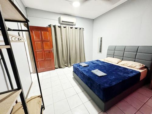 een slaapkamer met een bed met een blauwe deken bij MZ Homestay Tuaran in Tuaran