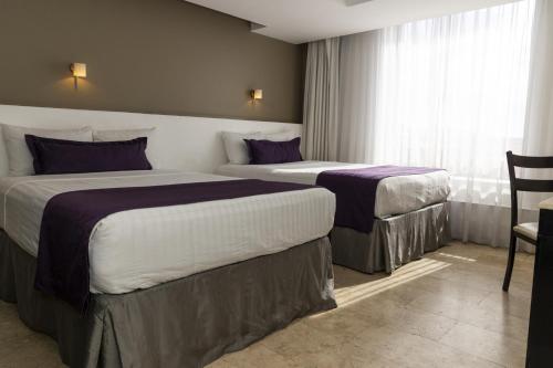 プエブラにあるGamma Puebla Señorial Centroのベッド2台と窓が備わるホテルルームです。