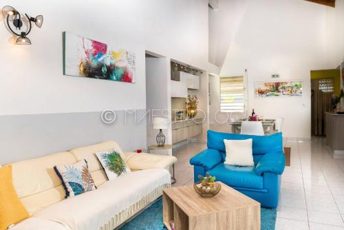 a living room with two couches and a table at Villa L'Artist en bord de mer avec piscine privée in Sainte-Rose
