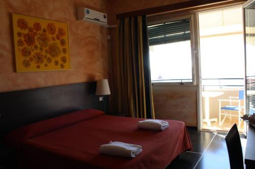 1 dormitorio con 1 cama roja y 2 toallas en Hotel Palace, en Varazze