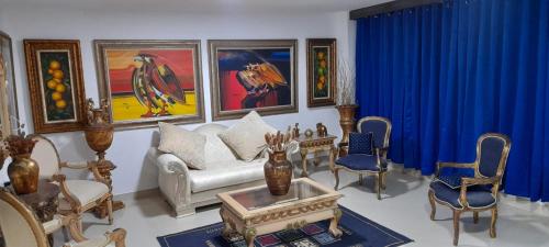 a living room with blue curtains and a couch and chairs at Hotel La Guajira - Centro Historico in Ríohacha