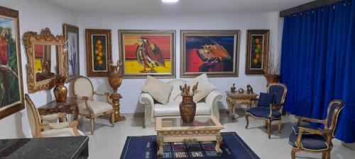 a living room filled with furniture and paintings at Hotel La Guajira - Centro Historico in Ríohacha