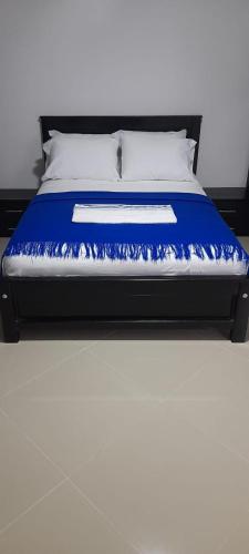 a bed with a blue and white blanket on it at Hotel La Guajira - Centro Historico in Ríohacha