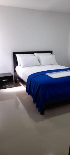 a bedroom with a bed with a blue blanket at Hotel La Guajira - Centro Historico in Ríohacha