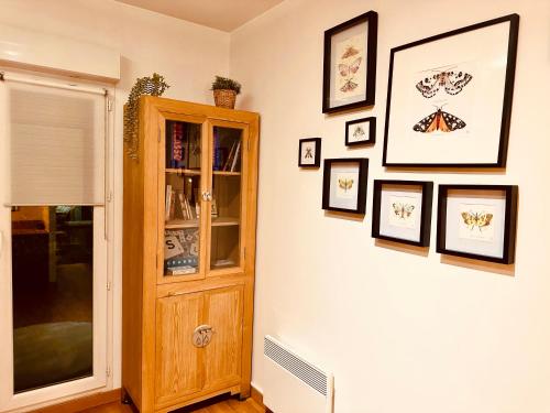a room with a cabinet and pictures on the wall at Accueillant et pratique, proche de Chantilly et du parc Asterix in Lamorlaye