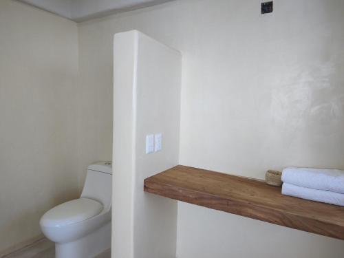 a bathroom with a toilet and towels on a shelf at Villas Roberto's Bistro Mirador in Troncones