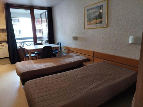 une chambre avec deux lits, une table et une fenêtre dans l'établissement Charmant studio avec balcon et parking, centre et thermes à 500m - FR-1-512-96, à Brides-les-Bains