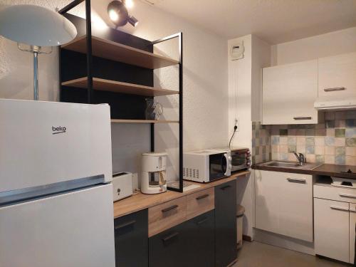 Il comprend une cuisine équipée d'appareils électroménagers blancs et d'un réfrigérateur blanc. dans l'établissement Charmant studio avec balcon et parking, centre et thermes à 500m - FR-1-512-96, à Brides-les-Bains