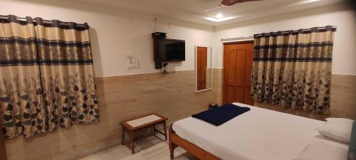 - une chambre avec un lit, une télévision et des rideaux dans l'établissement OYO 82374 Hanuman Residence, à Erragondapālem