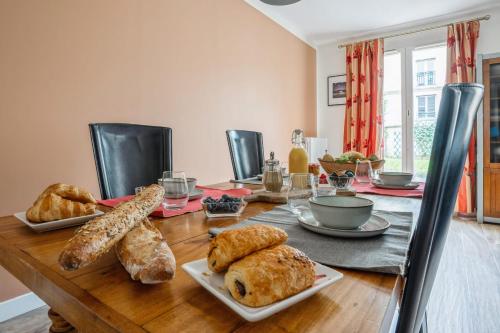 - une table en bois avec du pain et des viennoiseries dans l'établissement Nice house with garden in Versailles - Welkeys, à Versailles