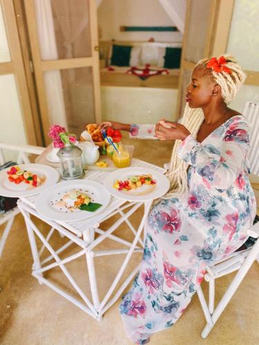 a woman sitting at a table eating food at Sharazad Boutique Hotel in Jambiani