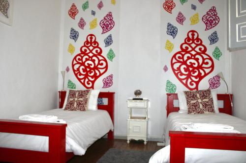 duas camas num quarto com decalques vermelhos e verdes em Very Typical - Alojamento Local em Elvas