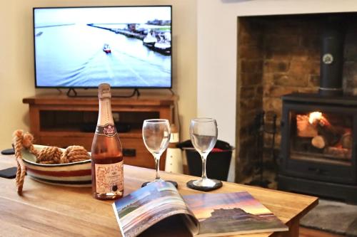a table with a bottle of champagne and two glasses at Kindly Light Cottage in Amble