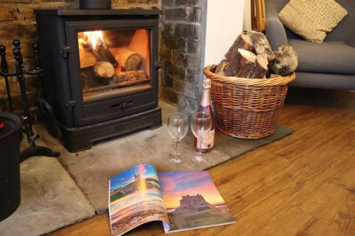 a book and a glass of wine and a fireplace at Kindly Light Cottage in Amble