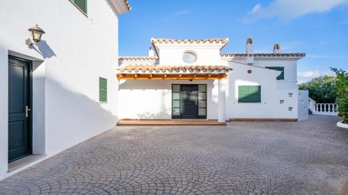 a white house with a cobblestone driveway at Villa Alma de Mar - Exceptional Villa with Marina Views & Pool in Port d'Addaia