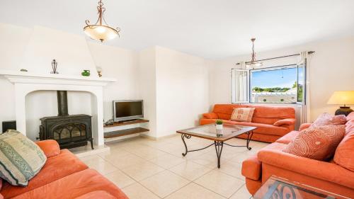 a living room with orange furniture and a fireplace at Villa Alma de Mar - Exceptional Villa with Marina Views & Pool in Port d'Addaia