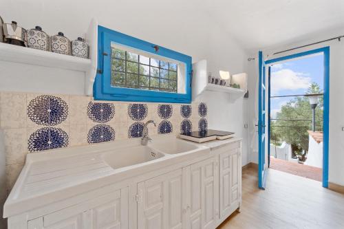 uma cozinha com um lavatório e uma janela azul em suite paradiso em Quartu SantʼElena