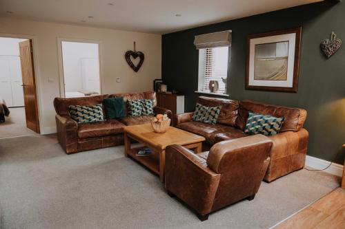 a living room with leather couches and a table at Pattys Barn Holiday Cottages, Cabins and Venue Hire in Cockerham