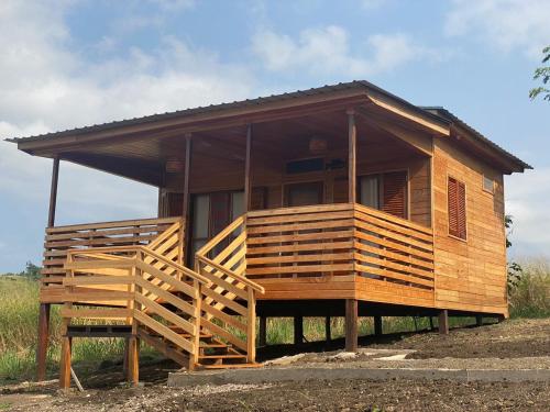 a large wooden house with a large deck at Monte Mar SãoTomé in M. Peixe