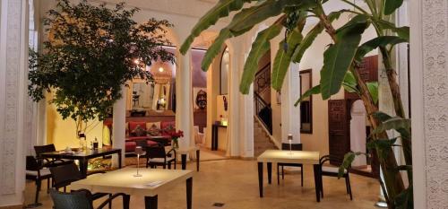 a restaurant with tables and chairs and a plant at Riad de Vincent in Marrakesh