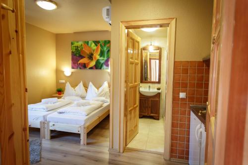 a bedroom with two beds and a bathroom with a sink at Hotel Karin in Budapest