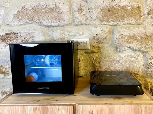 a microwave sitting on a table next to a stone wall at Casa Vacanze A un Passo dal Volo in Bari