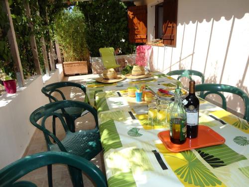 a table with green chairs and bottles of wine at Hôtel Punta e Mare des Chambres ou des Appartements T2 in Cargèse