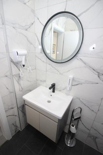 a white bathroom with a sink and a mirror at Villa Deny Mostar - with free parking in Mostar