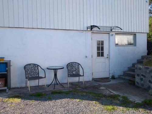 2 chaises et une table en face d'un bâtiment dans l'établissement Frivoll, 35 minutes walk to town., à Arendal