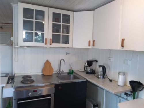 a kitchen with white cabinets and a sink at Frivoll, 35 minutes walk to town. in Arendal