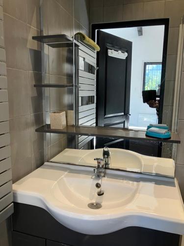 ein Bad mit einem Waschbecken und einem Spiegel in der Unterkunft Beau duplex climatisé dans une villa calme. in Peymeinade
