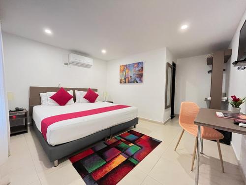 a bedroom with a large bed and a table and a desk at Hotel Vanguardia Natural in Villavicencio