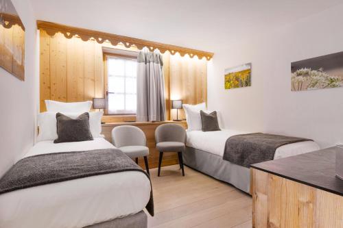 a hotel room with two beds and a desk at La Ferme du Golf in Megève