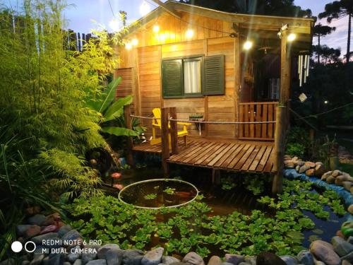 a tiny house in a garden with a pond at Chalé Cafofo in Campo Alegre