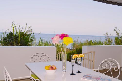 a table with a bowl of fruit and two wine glasses at Villa Ginestra sulla spiaggia di Stromboli in Stromboli