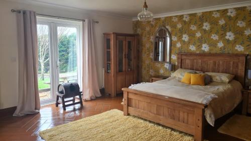 a bedroom with a large bed and a large window at Romantic rural cottage, log burner, Sky tv early check in ,large gardens in Llangefni