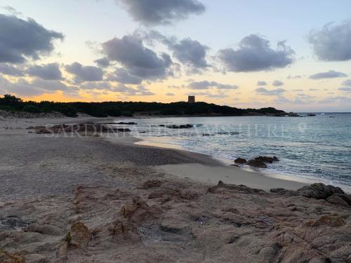 a beach with a lighthouse in the distance at Villetta Meraviglia a 100 m dalla spiaggia in Vignola Mare