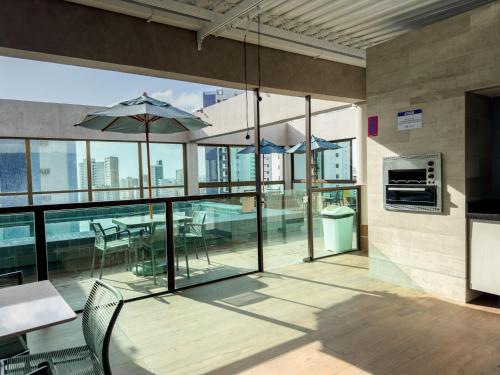 a patio with a table and umbrella on a building at Flat em Boa Viagem Rooftop 470 Conforto e Localização privilegiada in Recife