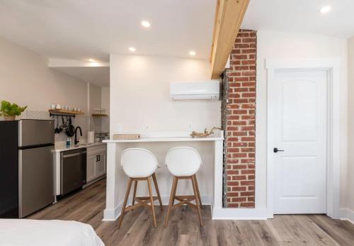a kitchen with two white bar stools in front of a brick wall at Beachwalk #5 8 Mins to Beach in Virginia Beach