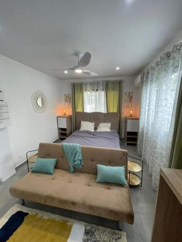 a bedroom with a bed and a couch with blue pillows at Le refuge rafraîchissant in Montjoly