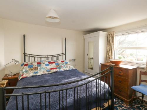 sypialnia z łóżkiem z niebieską kołdrą i oknem w obiekcie Chenies w mieście Weymouth