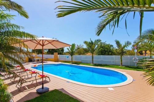 - une piscine avec un parasol, des chaises et une table dans l'établissement Villa Ocean Bliss by Algarve Vacation, à Albufeira