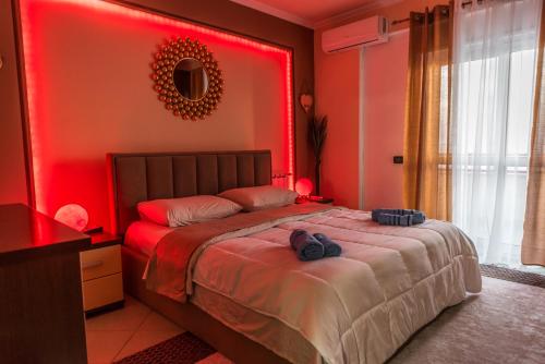 a red bedroom with a bed with two pairs of shoes on it at Full Sea View Center 2 Bedroom in Durrës