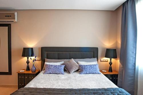 een slaapkamer met een groot bed met blauwe kussens bij Elegante apartamento zona arenal in Platja de l'Arenal