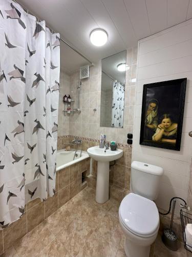 a bathroom with a toilet and a sink and a shower curtain at Fresh and cozy apartmrent in Yakkasaray