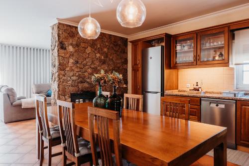 a kitchen with a wooden table and a refrigerator at A Nossa Casa in Castelejo